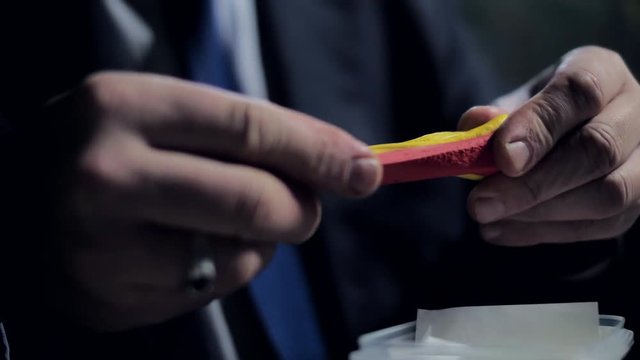 closeup middle-aged man mixes yellow and red play dough
