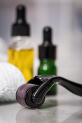 Dermaroller, Handtuch, gelbe Pflege Öl und grüne Serum Flaschen zum  Microneedling für Anti...