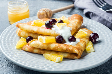 A portion of pancakes with berries and cream on the plate.
