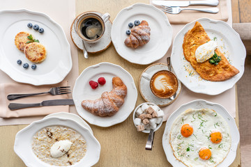 Breakfast. Croissants, coffee and many different dishes on the table in the restaurant. Frittata - italian omelet. Omelette with tomatoes, avocado, spinach and soft cheese.