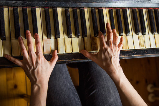 Close up fingers of woman pianist at the rusty piano keys, arms plays solo of music. Hands of female musician playing, overhead shot