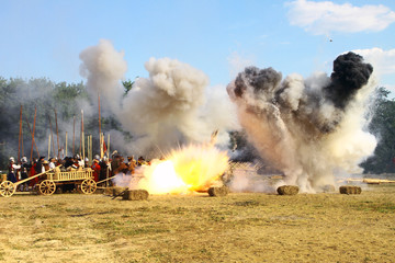 Fototapeta na wymiar Massive bomb explosion during re-enactment of medieval battle. Blowing up on the battlefield with flame and clouds of white and black smoke. Detonation of the cannon ball. Living history festival. 