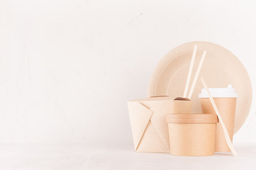 Blank different cardboard packaging for fast food - bowl, drink cup, box for noodles, cutlery, chopsticks, plate on white wood shelf, copy space.