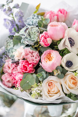beautiful fresh cut bouquet of mixed flowers in vase on wooden table. The work of the florist at a flower shop. Delicate Pastel tones color