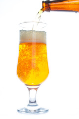 Beer is pouring into a glass from bottle on white background