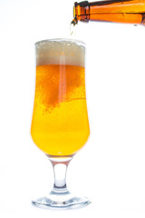 Beer is pouring into a glass from bottle on white background