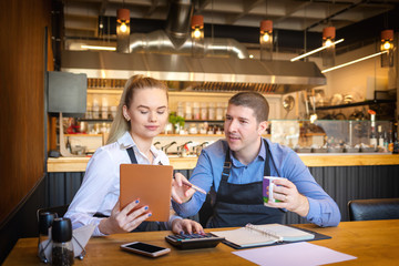 Small family restaurant owners discussing finance calculating bills and expenses of their small business. - 247294853
