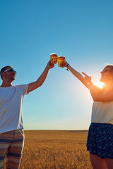Fototapeta na wymiar Young couple drinking beer outdoors and enjoying summertime.