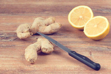 Female hands cut into pieces ginger root for a drink made from fresh lemon and ginger on brown...