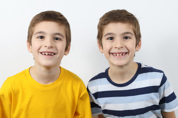 Portrait Of Cute Twin Brothers Wide Smiling Showing Growing Permanent Teeth On White Background