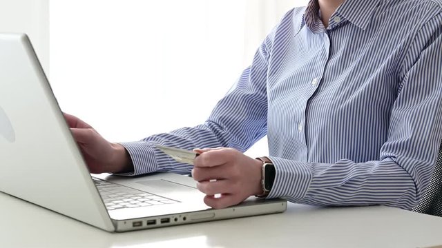 ネットショッピングでクレジットカード決済をする女性。手元のクローズアップ。