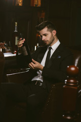 Attractive man wearing black tuxedo in whiskey bar.