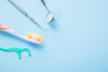 Dental health and teethcare concept. Dentist tools. Professional steel dental instrument with a mirror, toothbrush and dental floss on light blue background with free space.
