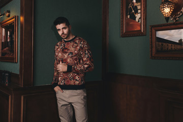 Young bearded male doing fashion shooting in vintage bar. 