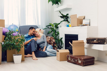 Fototapeta na wymiar Housewarming. Young couple in a new house, apartment. Man amd woman sitting beside carboard boxes