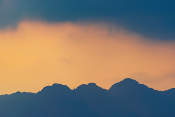 Orange and yellow sunset with mountains silhouettes. Gradient vivid nature background