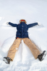 Fototapeta na wymiar Young teenager boy makes figures on snow and has fun. Active lifestyle, winter activity, outdoor winter games