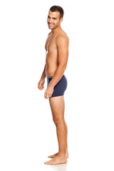 Fototapeta premium Shirtless handsome smiling man in panties on white background