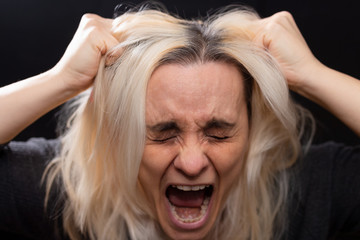 Blonde woman screaming and pulling her hair with her hands