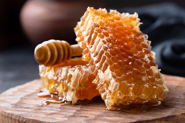 Honeycomb and honey dipper on wooden board. Selective focus. Raw honey, Natural honey