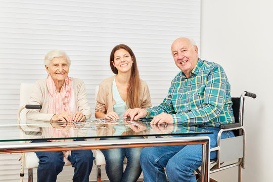 Senioren und junge Frau spielen Puzzle spielen