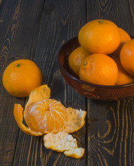 Tangerines in the bowl on wooden background