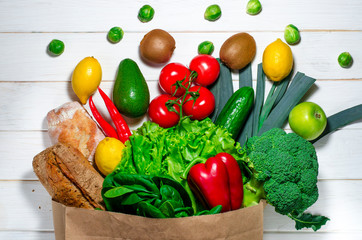 Paper bag of different health food on white wooden background. Top view.