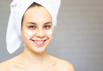 Attractive Young Woman Wrapped with Bath Towels and cream on the face	
