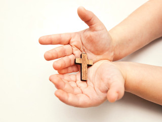 A little wooden cross in the child's hands