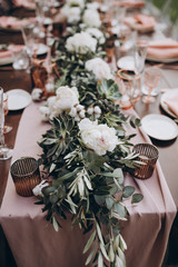 in the backyard of the villa in Tuscany there is banquet wooden table decorated with flowers and...