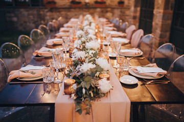 in backyard of villa in Tuscany there is banquet wooden table decorated with cotton and eucalyptus...