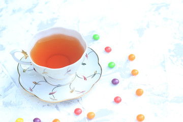 Cup of tea with sweets on a light background.