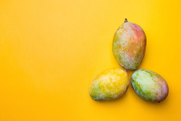 Fresh mango over yellow background or wallpaper, top view with copy space