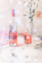 Two glasses and bottle of rose wine on light background.