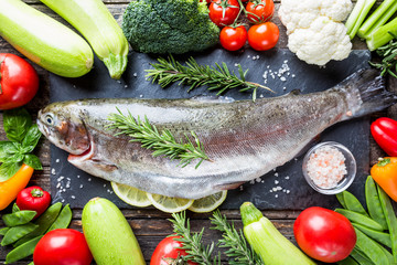 Raw Trout fish with fresh vegetables ingredients for healthy clean cooking, top view