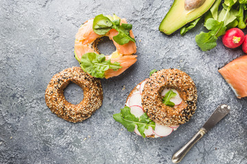 Bagels with cream cheese avocado, fish, arugula and radish. Healthy breakfast food. Top view.