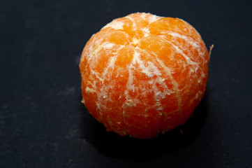 Fresh peeled mandarin orange on dark background