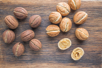 Delicious walnut shaped shortbread sandwich cookies filled with sweet condensed milk on old wooden background, top view