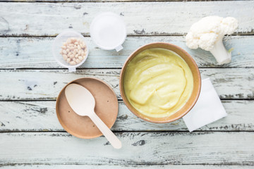 Cauliflower soup puree on a white wooden background, top view. Vegetarian healthy food concept