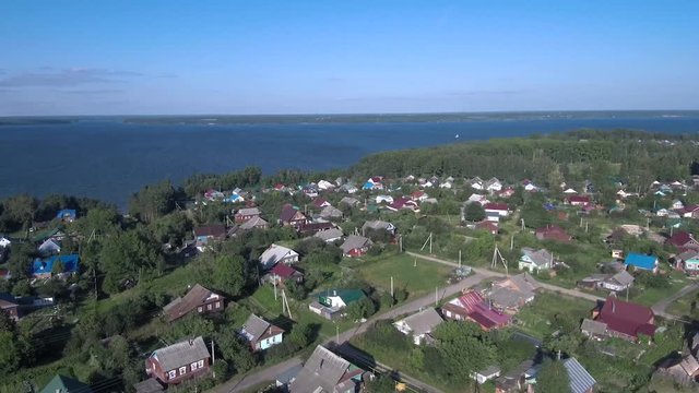 streets with one-story houses and vegetable gardens on the banks of a large river, view from the quad copter