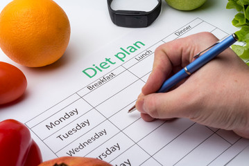 The doctor writes a prescription to the patient, makes a diet plan in the workplace with fresh...