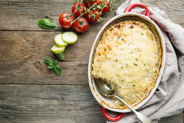 Casserole with chicken and zucchini on old wooden background, top view