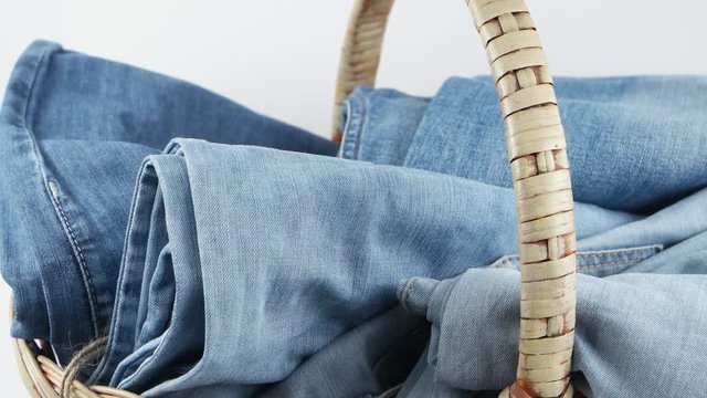 Wicker basket with blue jeans against the white background
