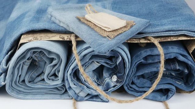 Blue jeans folded compactly in a paper bag, background