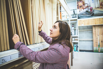 Woman at home building material choosing wood to renovate her home. Girl looking at choosing laminae from laminate finish texture inside the store for construction or renovation