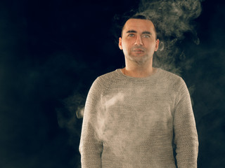 smoking man in e-cigarette smoke on black background
