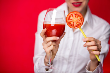 woman drinking tomato juice and and holding a piece of tomato like lollipop 