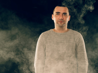 smoking man in e-cigarette smoke on black background