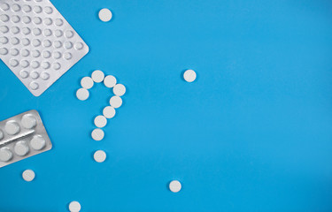 Medical background with multi-colored packs of pills. Сoncept pharmacy, clinic, drugs, headache medicine. Image on illness, flu, treatment. White question mark from pills