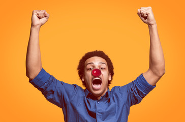 Fototapeta premium The happy surprised and smiling afro man on red nose day. The clown, fun, party, celebration, funny, joy, holiday, humor concept